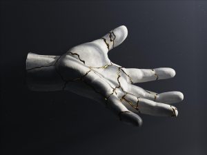 A statue of a hand reaching out, that has been broken and glued back together with gold